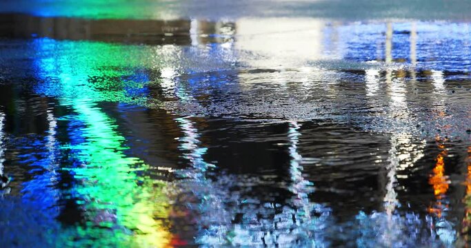 Little rain in the city. Beautiful colored lights of working Ferris wheel reflect on puddles. Cinema 4K 60fps 30 second relax video
