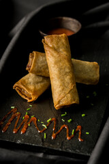 delicious spring rolls on a black plate