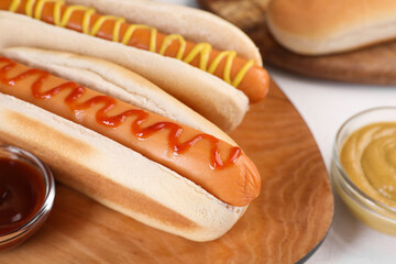 Tasty hot dogs with ketchup and mustard on white table, closeup