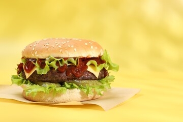 Burger with delicious patty on yellow background, space for text