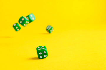 Many green game dices falling on yellow background. Space for text