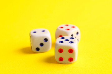 Three white game dices on yellow background, closeup