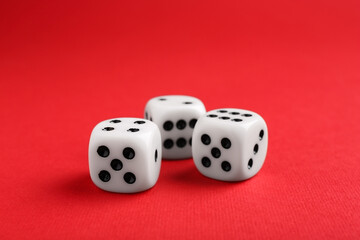 Three white game dices on red background, closeup