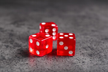 Three red game dices on grey textured table, closeup