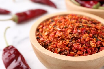 Chili pepper flakes in bowl on table, closeup