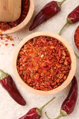 Chili pepper flakes and pods on light textured table, flat lay