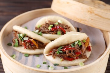 Delicious gua bao (pork belly buns) in bamboo steamer on table, closeup