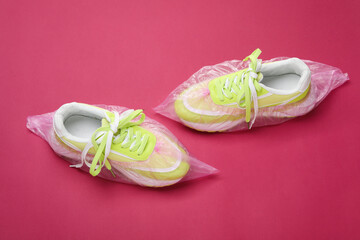 Sneakers in shoe covers on pink background, above view