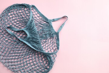 Blue string bag on pink background, top view. Space for text