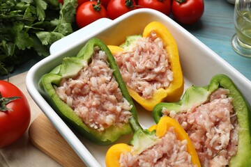 Raw stuffed peppers and ingredients on light blue wooden table, closeup