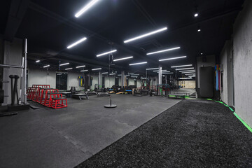 An empty modern gymnasium with a variety of equipment, offering a spacious, functional, and...