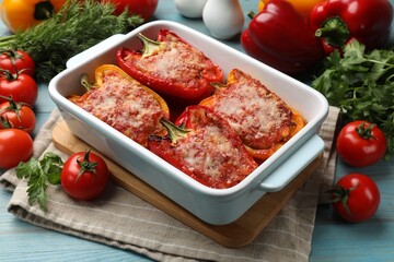 Tasty stuffed peppers in dish and ingredients on light blue wooden table