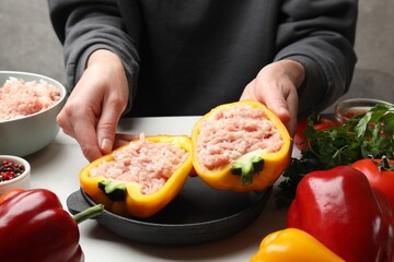 Woman making stuffed peppers with ground meat at white table, closeup