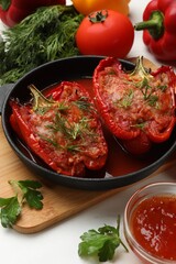 Tasty stuffed peppers in dish and ingredients on white table