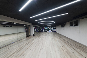An empty dance hall with a glass wall adorned with decorative graffiti, offering a fusion of...
