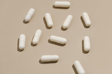 Close-up of pattern of white natural capsule pills on beige isolated background. Concert of pharmacy, dietary supplements, health and drugs for diseases. Image for your design