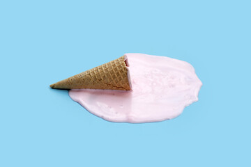 Melting ice cream ball with waffle cone on blue background.