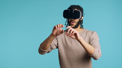 Middle Eastern man wearing virtual reality headset, doing swiping gestures. BIPOC person using high...