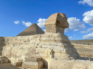 Great Sphinx including pyramids in the background on a clear sunny, blue sky day in Giza, Cairo, Egypt with no people