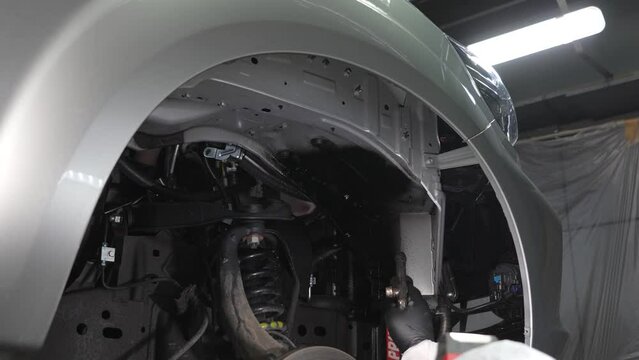 The master sprays an anti-corrosion compound on the bottom of the car. 