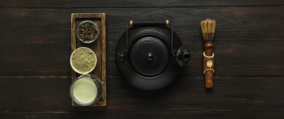 Composition with matcha tea, chasen and teapot on dark wooden background