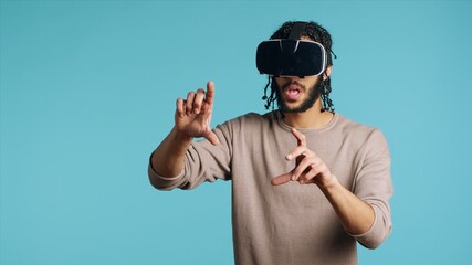 Tech enthusiast wearing virtual reality goggles, doing swiping gestures. BIPOC man using high tech...
