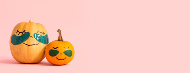 Pumpkins with drawn faces and under-eye patches on pink background