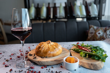bread bowl with pilaf on wooden board and vegetables and red luxury wine glass