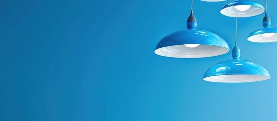some lamps hanging from the white ceiling that look like UFOs. The lamps are blue and one of them stands out on a blue background.