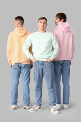 Young men in stylish jeans on light background