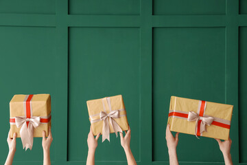 Female hands holding Christmas gift boxes on green background