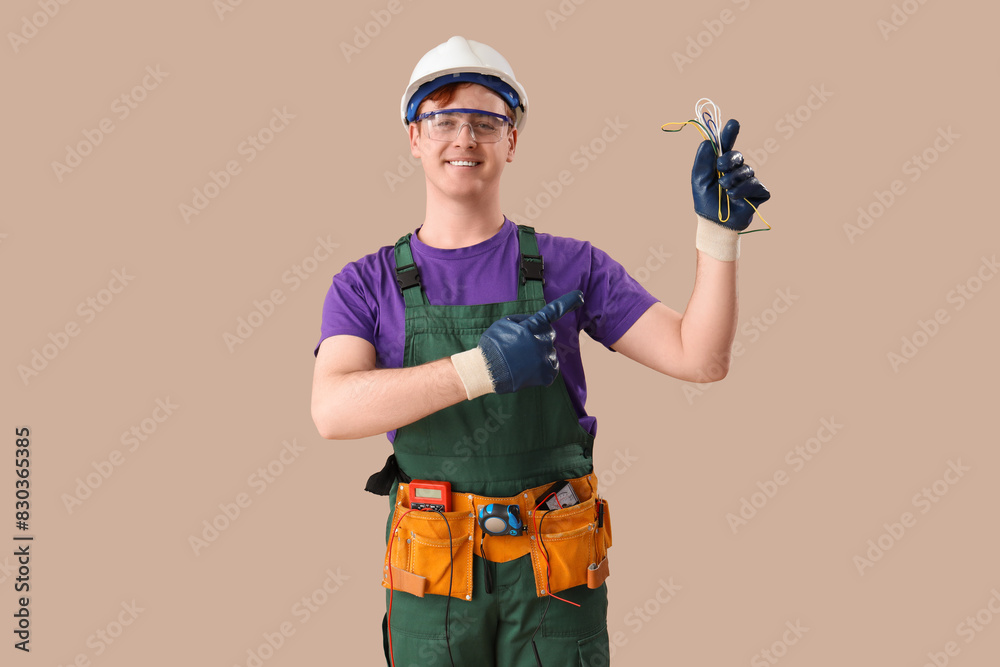 Sticker Male electrician pointing at cables on brown background