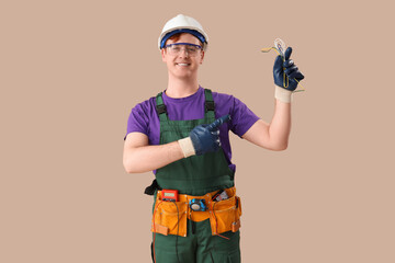 Male electrician pointing at cables on brown background