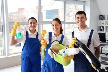 Young janitors with cleaning supplies in office