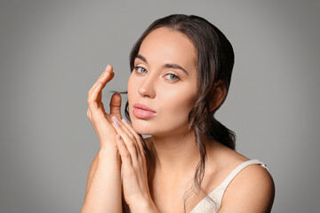 Beautiful young woman with natural makeup against grey background