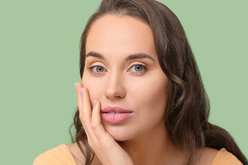 Young woman with natural makeup on green background, closeup