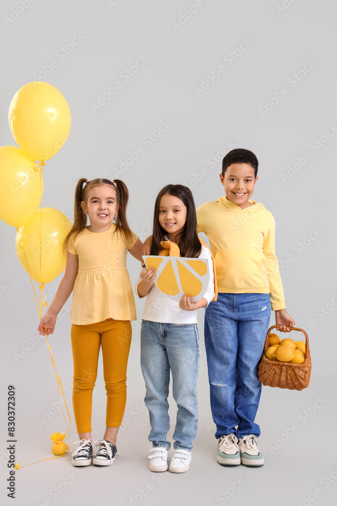 Wall mural cute little children with lemons for lemonade and balloons on light background