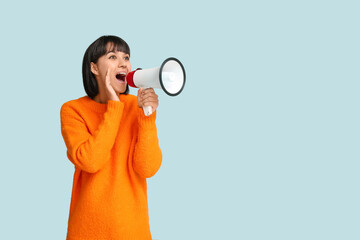 Young woman with megaphone  on blue background