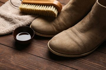 Brush, boots, cloth and shoe polish on wooden background