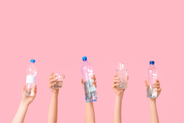 Female hands with glasses and bottles of water on pink background