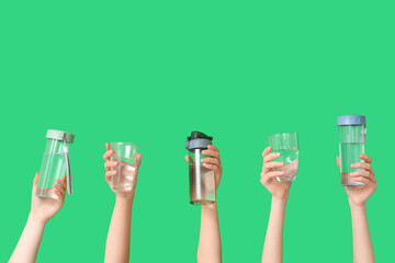 Female hands with different glasses and  bottles of water on green background