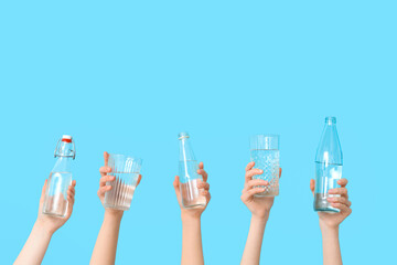 Female hands with glasses and bottles of water on color background