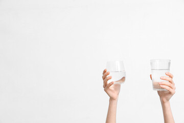 Female hands with glasses of water on white background, closeup