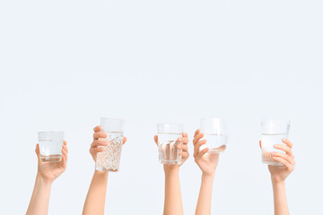 Female hands with different glasses of water on white background