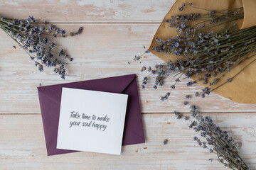 Paper card note with text TAKE TIME TO MAKE YOUR SOUL HAPPY from violet envelope. Lavender flower....