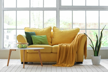 Interior of stylish living room with yellow sofa, coffee table, houseplant and window