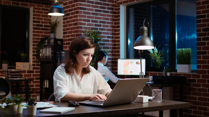 Businesswoman working overtime for company project, doing tasks in office overnight. Employee...