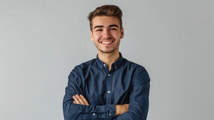Obraz premium A man in a blue shirt smiling with his arms crossed. Suitable for business or casual concepts