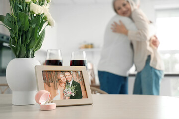 Picture of couple celebrating their wedding anniversary with rings and wine on table in kitchen