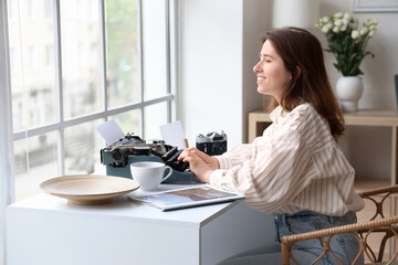 Young woman typing on vintage typewriter at home